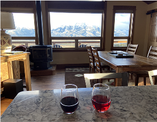 Two stemless glasses of wine on a countertop in a mountain cabin. Showing how amazing sustainably grown wine can be in the places you love.