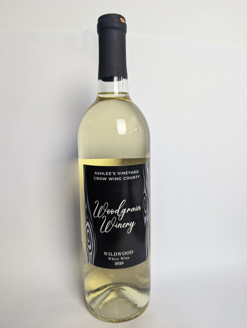 This is a picture of woodgrain winerys white wine named Wildwood. The bottle is standing vertically and has a black lable with silver metal flake woodgrain. The words on the label are white. The image views the bottle from the front.