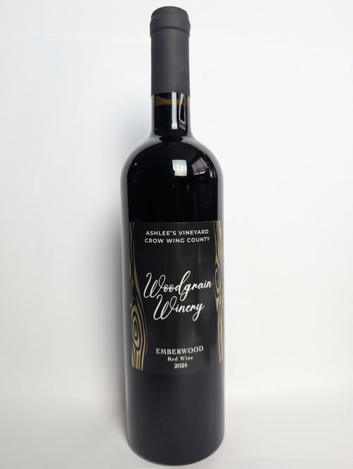 This is a picture of woodgrain winerys red wine named Emberwood. The bottle is standing vertically and has a black lable with gold metal flake woodgrain. The words on the lable are white. The image views the bottle from the front